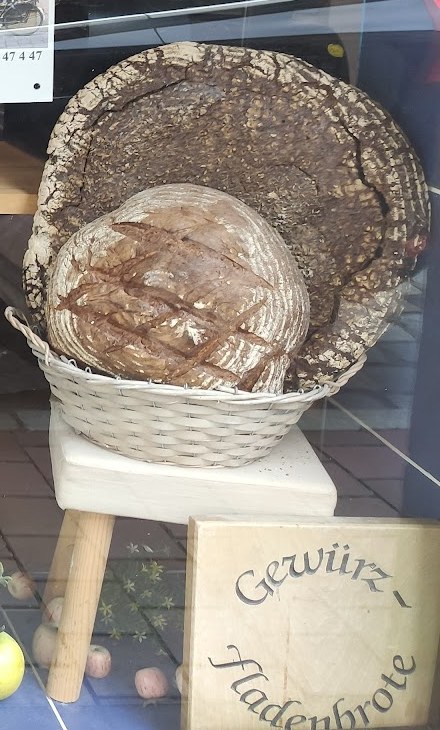 Großer Laib im Korb vor einem Holzschild mit der Aufschrift „Gewürz-Fladenbrote“
