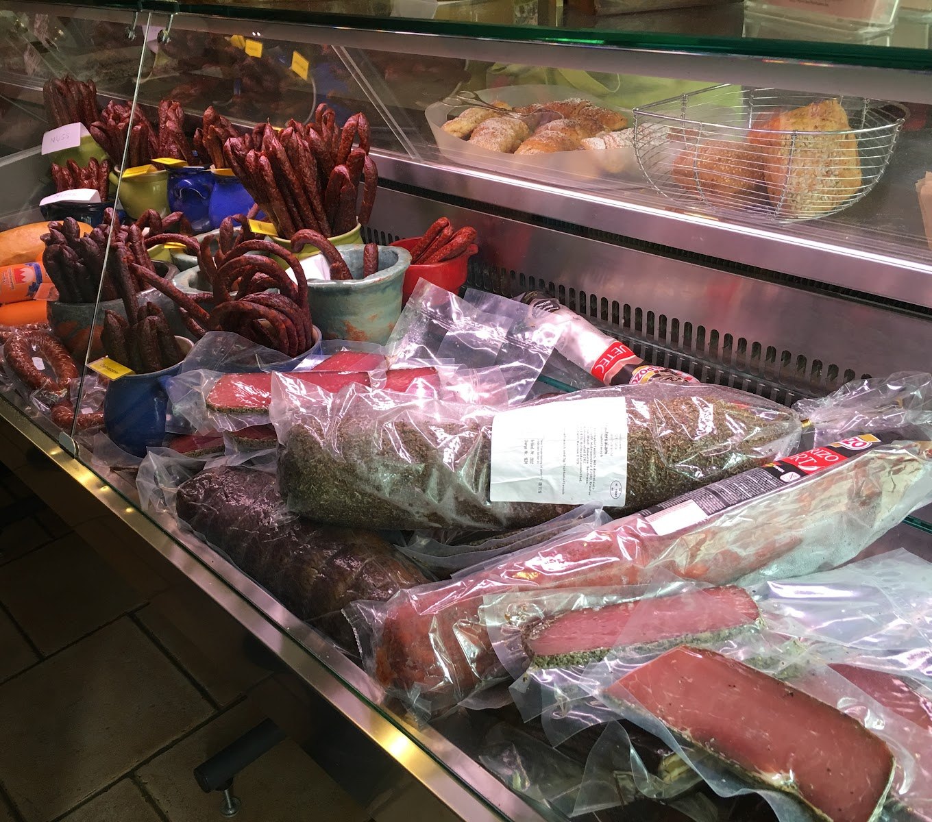 Wursttheke mit Beißern in Steinguttöpfen, Schinken und eingeschweißter Salami
